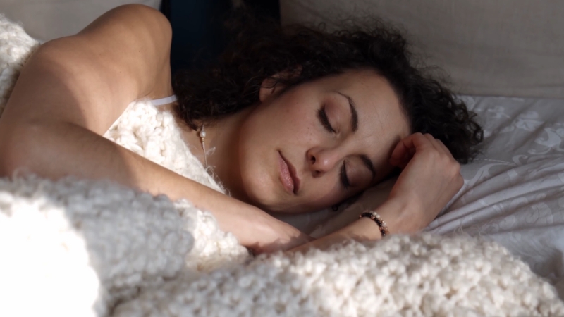 Osoba mirno spava na boku, pokrivena ćebetom