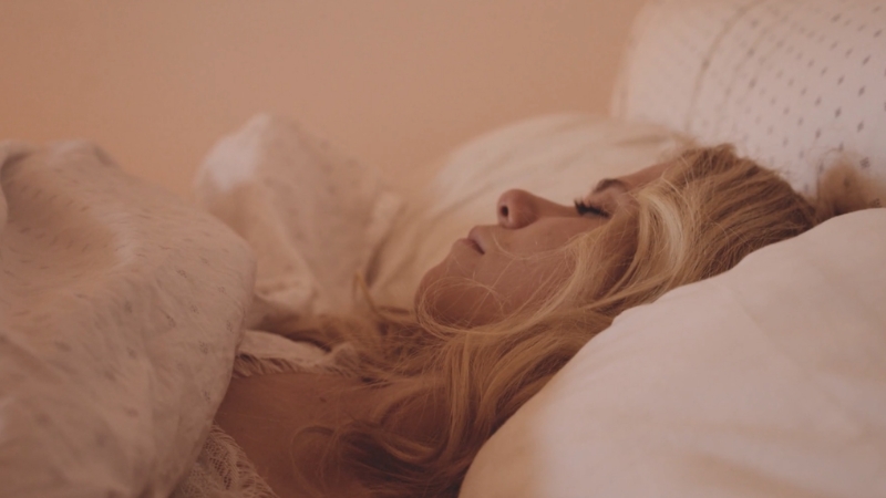 Žena mirno spava na jastuku, pokrivena ćebetom